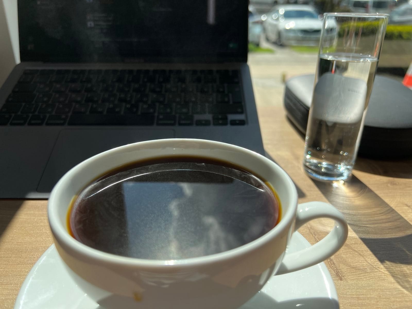 Everything is usual on this photo: a Mac, a cup of coffee, a glass of water